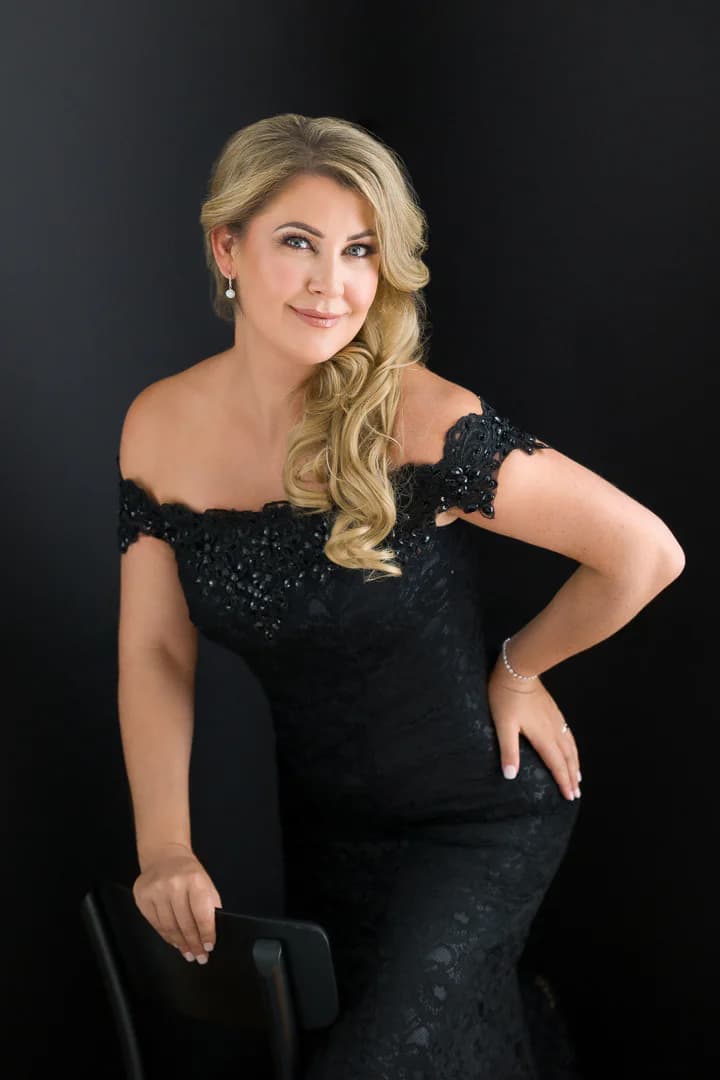 Erin Ashlee Rose in a formal black dress against a dark studio background